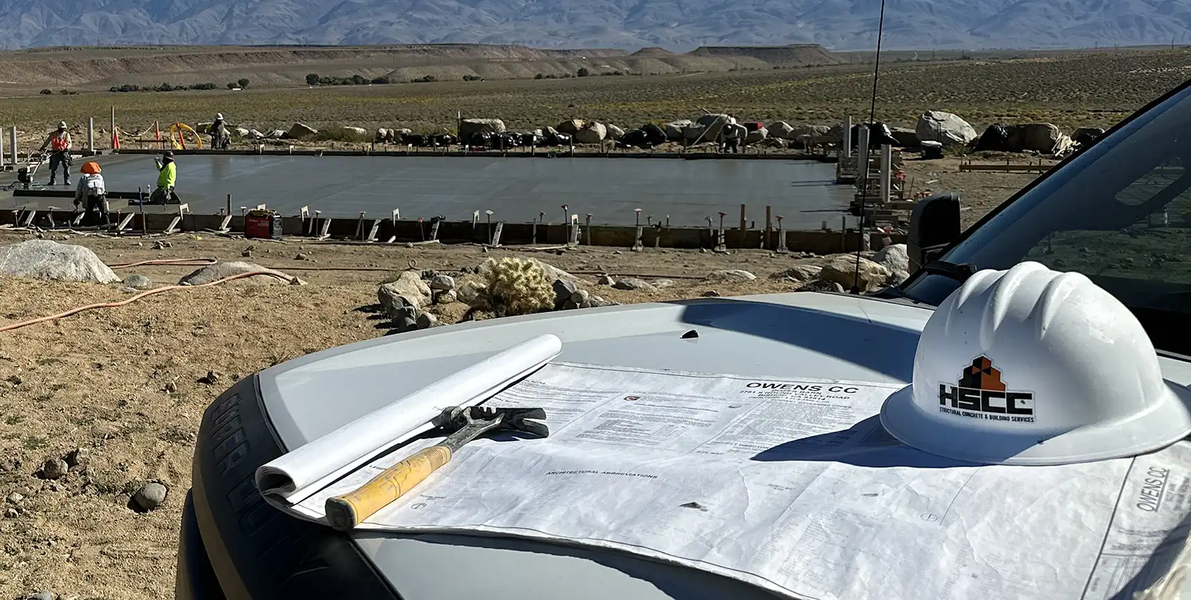 Plans and a hardhat on the hood of a worktruck